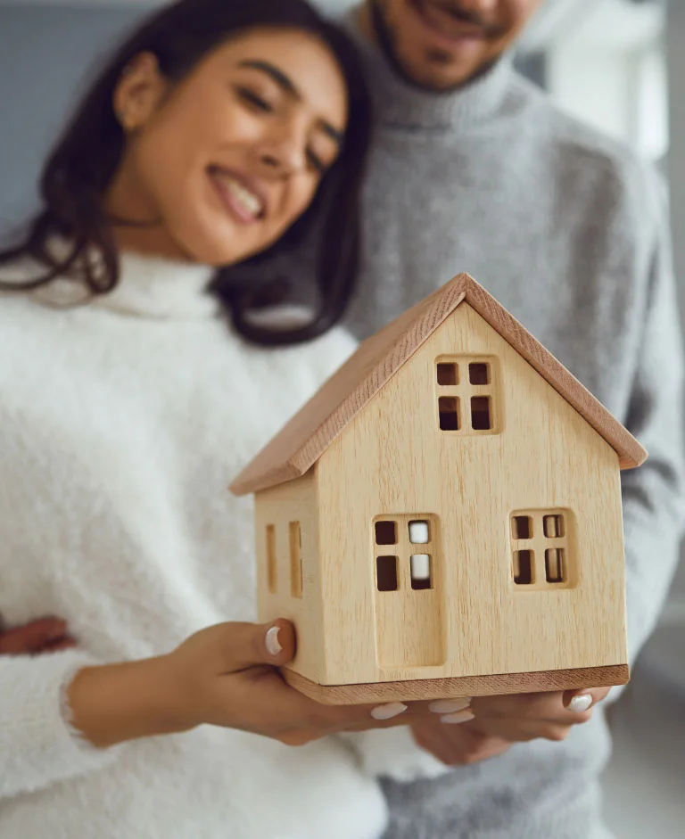 Couple tenant une petite maison en bois.